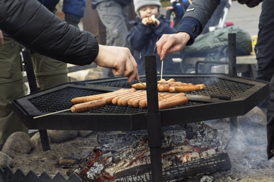 A group of people grilling hot dogs on a grill