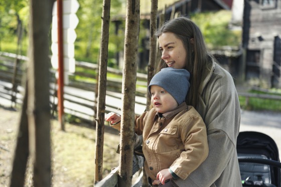 En mamma och hennes barn tittar på fåren på Skansen